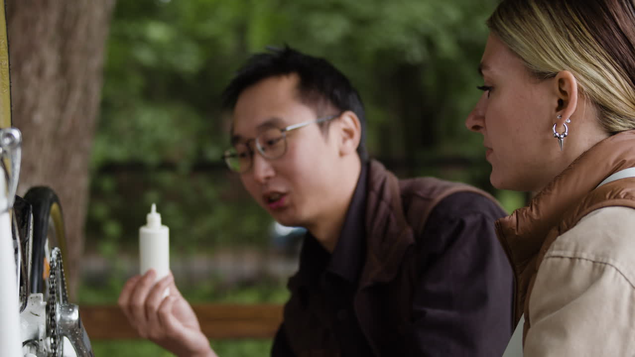 People repairing a bicycle outdoors