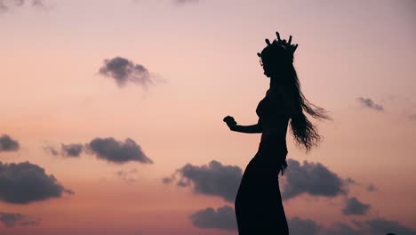 close up of sexy, elegant and erotic arabian woman performing belly dance on the beach during golden hour. silhouette. side view