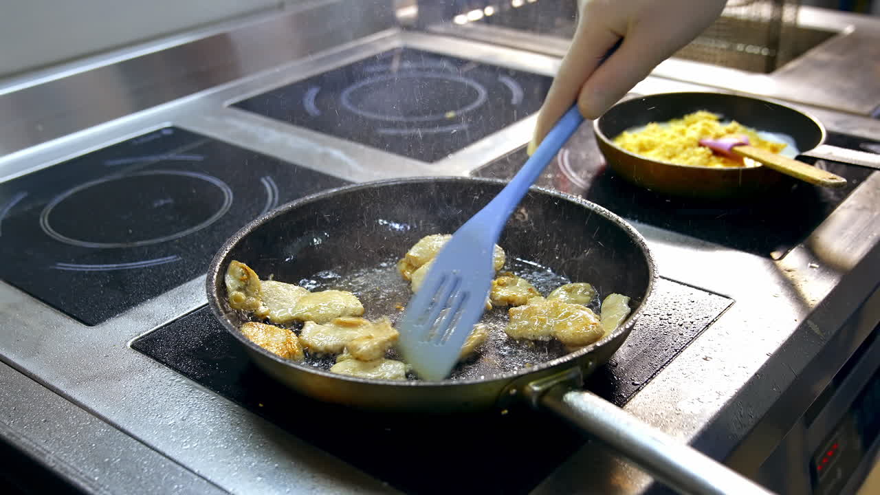 Fillet of sea white fish fried on a pan. Unrecognizible chef mixes dish with spatula. Appetizing and delicious seafood dish.