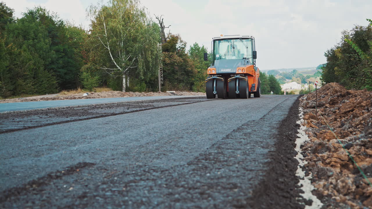 Road construction equipment machines. Asphalt roller paving new road in the countryside