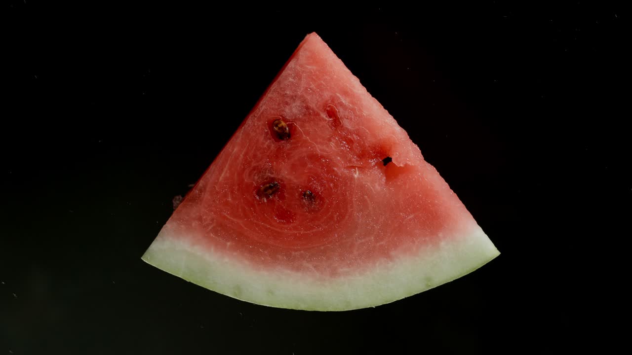 triturar una rebanada de sandía sobre un fondo negro