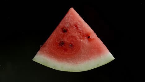 triturar una rebanada de sandía sobre un fondo negro