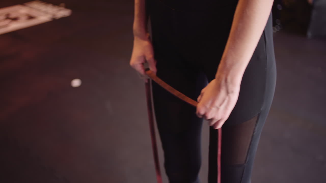 Determinata giovane donna snella che allena braccia e bicipiti con una fascia di resistenza in palestra 2