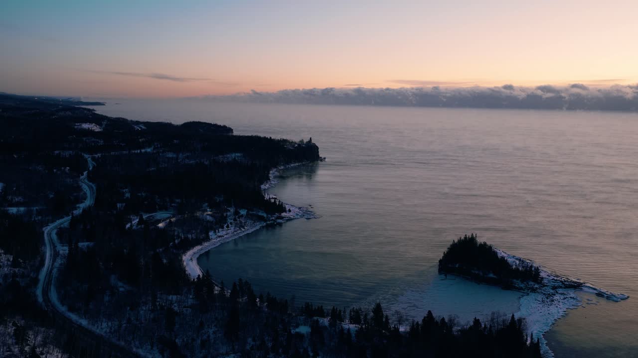High-altitude aerial view of the frozen North Shore coastline and islands on Lake Superior at the start of a winter dawn