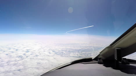 view from the cockpit of a private jet at cruising flight level with another aircraft passing by producing contrails