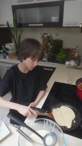 boy cooking pancakes in a kitchen