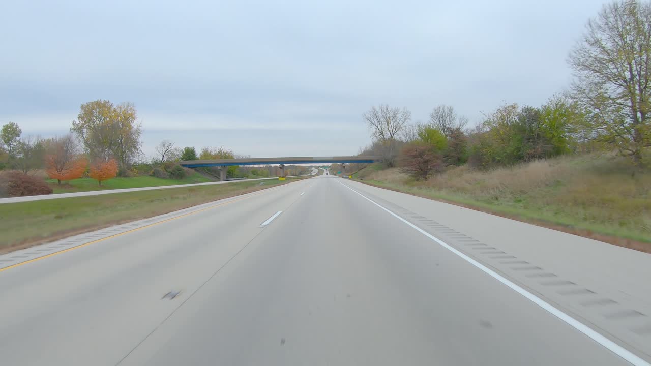 pov conduciendo en una carretera interestatal pasando por campos cosechados en un día nublado de invierno en la zona rural del oeste de illinois