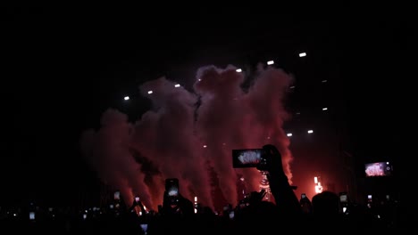 spectacular night concert: slow-motion footage of colorful animated stage on fire and smoke, as excited crowds applaud in awe