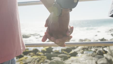 close up of senior african american couple holding hands on promenade by the sea, slow motion