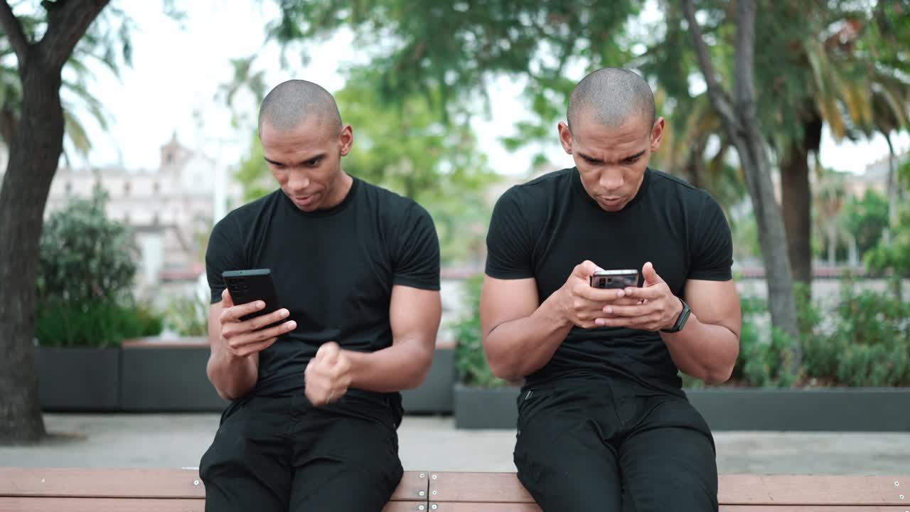 Serious bald brothers typing on phones on bench