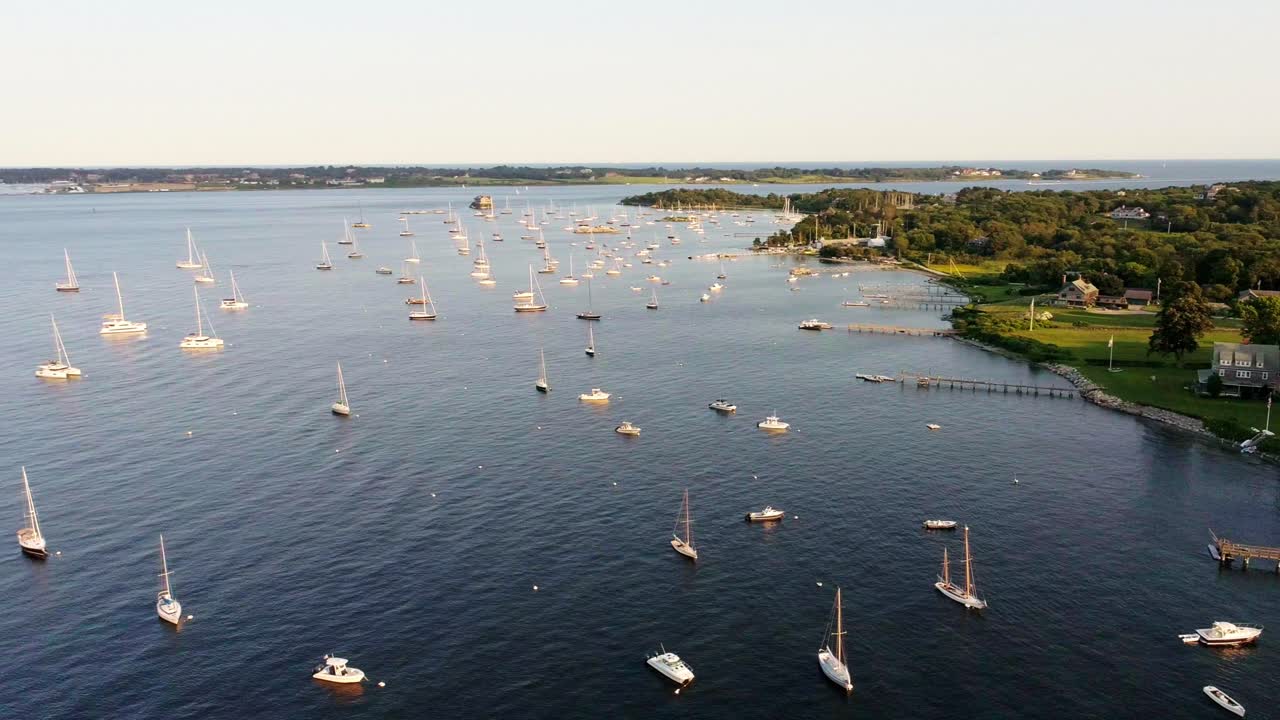 Luftopptak som sirkler seilbåter fortøyd i bukten med eiendommer ved vannkanten i Jamestown Rhode Island
