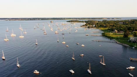 Aerial-circling-of-sailboats-docked-in-bay-with-waterfront-property-in-Jamestown-Rhode-Island