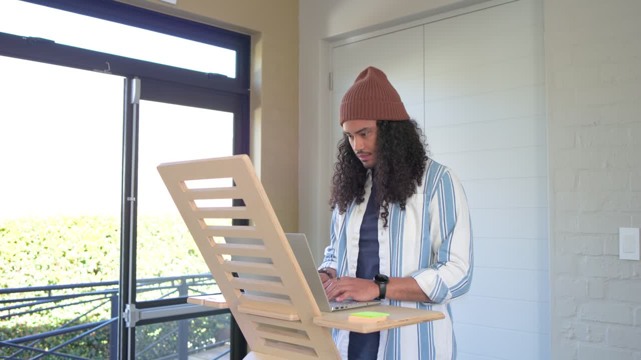 Uomo di mezza età motivato che lavora da casa, digitando al laptop e sorridendo mentre guarda l'orologio