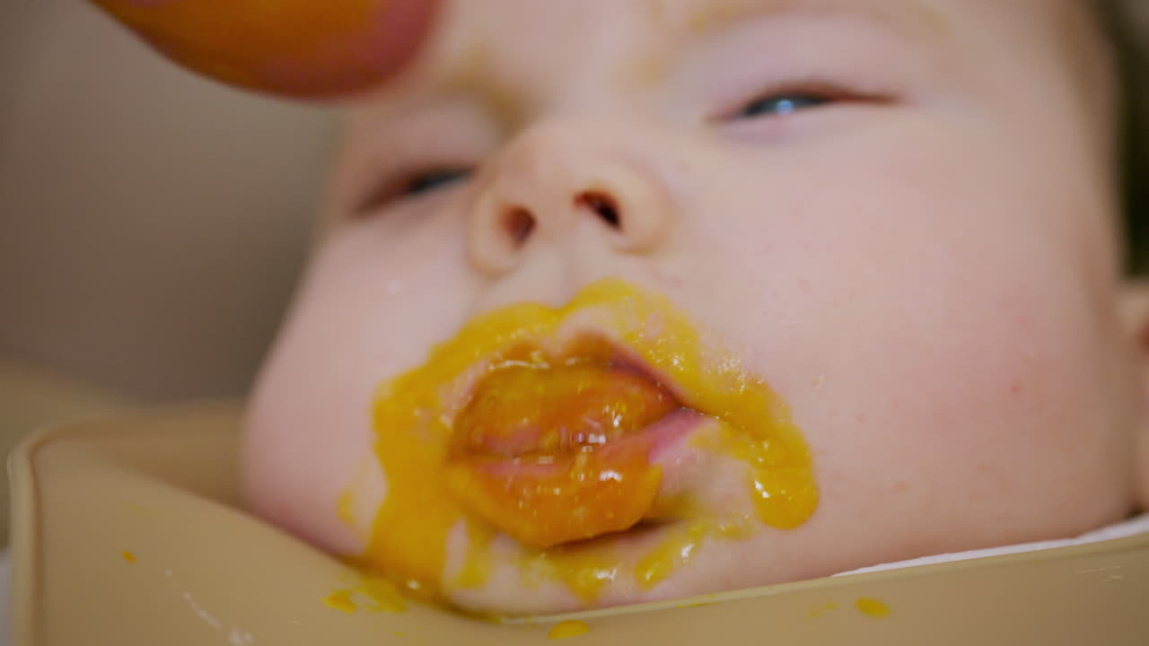 スプーンで離乳食を与えられている赤ちゃんのクローズアップ。顔の細部と穏やかな表情が見える。