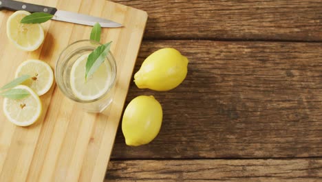 video of glass with lemonade and lemons on wooden board and wooden surface