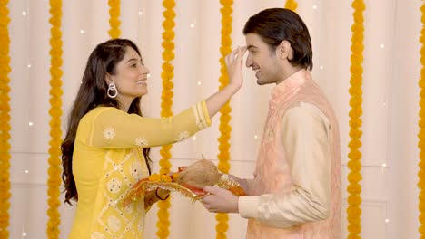 chica india poniendo tilak en la frente de su marido