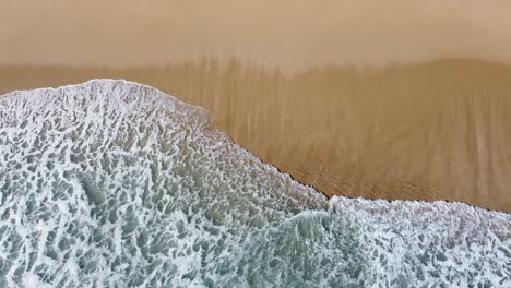 Una-Ola-Espumosa-Que-Llega-A-La-Playa-De-Arena-Y-Captura-La-Vista-Aérea-Y-Tranquila-De-La-Naturaleza.