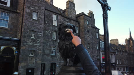 Der-Finger-Einer-Frau-Tritt-In-Den-Rahmen-Ein,-Um-Die-Nase-Der-Bobby-Statue-Des-Berühmten-Greyfriar-Auf-Der-Candlemaker-Row,-Edinburgh,-Lothian,-Großbritannien,-Zu-Berühren