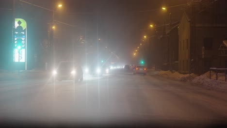 escena nevada de la calle principal llena de coches en la noche de invierno, riga, letonia