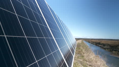 primer plano de paneles solares en un campo junto al río.