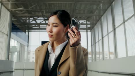 businesswoman using smartphone in modern city walkway