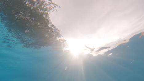 Action-cam-underwater-shot-looking-up-at-the-sun-through-crystal-clear-waters