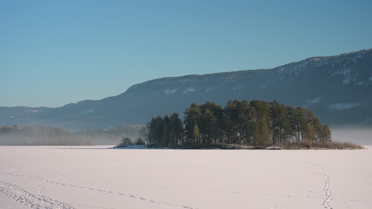 Frozen lake in Norway. Winter wonderland scenery, with mist and blue sky