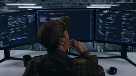 back view of tired asian military yawning before sleeping while write code with multiple computer screens in data center