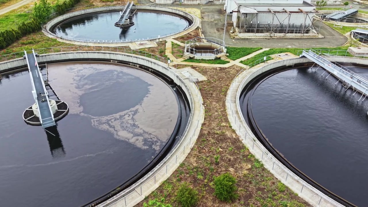 Industrial plant with water recycling and environmental control. Circular tanks process wastewater while environmental measures ensure safety and sustainability