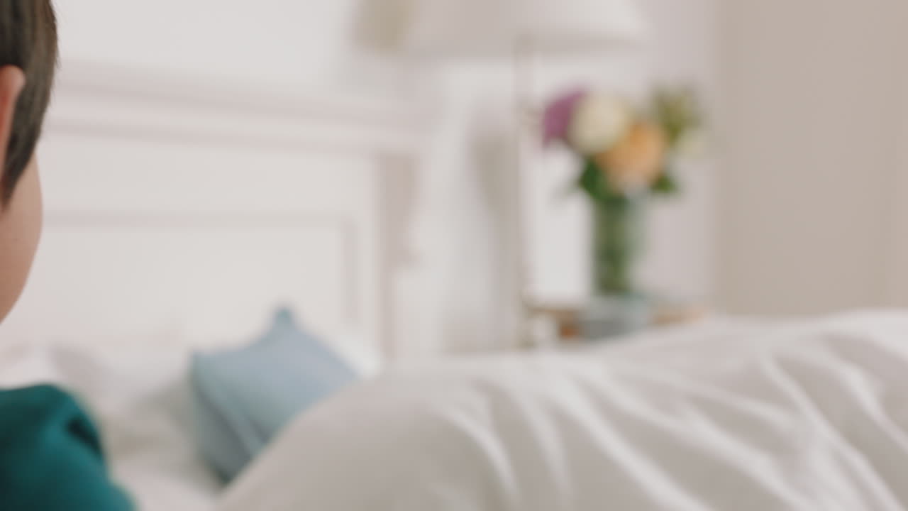 행복한 아시아 가족과 아이들이 침대에 뛰어들고 엄마와 아빠와 함께 놀고 주말 아침에 재미를 느끼고 흥분된 어린 아이들이 부모와 함께 집에서 게임을 즐기고 있습니다. 4k 영상