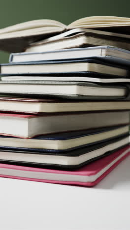 vertical video of open book on stack of books on green background, in slow motion