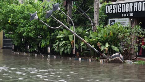 Severe cyclonic storm damage with broken electric pole with high voltage wire hanging dangerously at city residential area at Kolkata. Rain water logged road, due to Super cyclone Amphan.