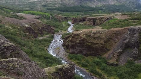 mountain river flow through hilly landscape of iceland, aerial view