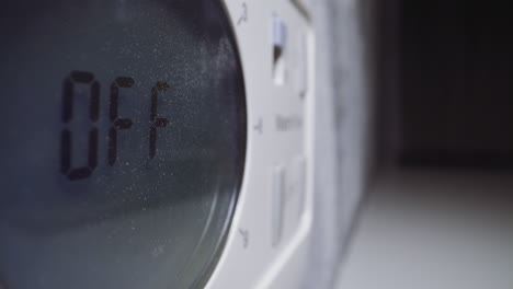 lady switches off timer on control panel of microwave oven