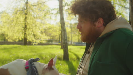 man interacting with his dog in a sunny park