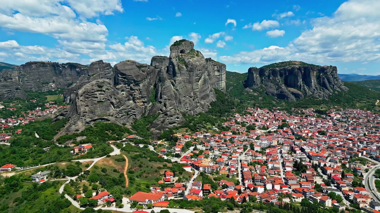 Bulutlu mavi gökyüzünün altında bir dağ kasabasının manzaralı görünümü