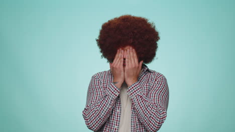 shocked young adult man closing eyes with hand showing stop gesture, confused shy scared to watch