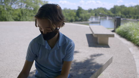 Teen-Boy-Im-Park-Nimmt-Maske-Und-Sonnenbrille-Ab-Und-Schaut-In-Die-Kamera