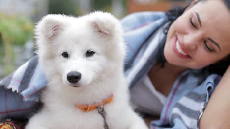 beautiful brunette with a dog uses a laptop and looks at it girl warms a white dog on an autumn day