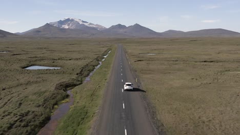 el coche viaja por un largo camino en medio del paisaje islandés con vistas infinitas