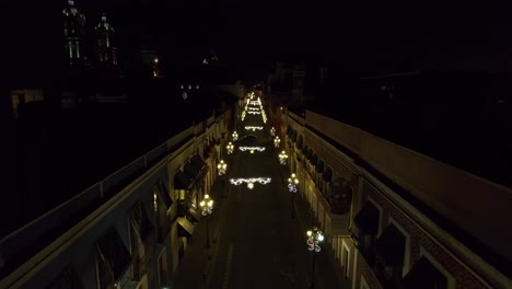 drone footage of the christmas light decorations in the streets of puebla méxico with the cathedral in the background