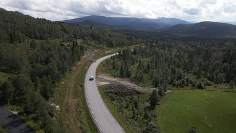 aerial drone shot of car driving in the road near the mountain and valley