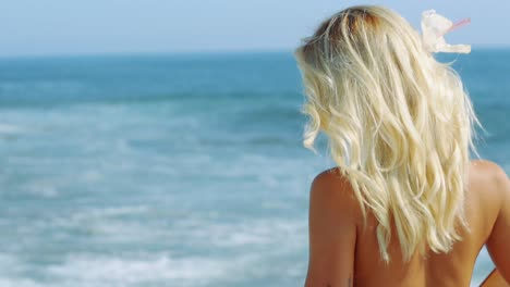 back shot of blonde model walking in her bikini by the sea