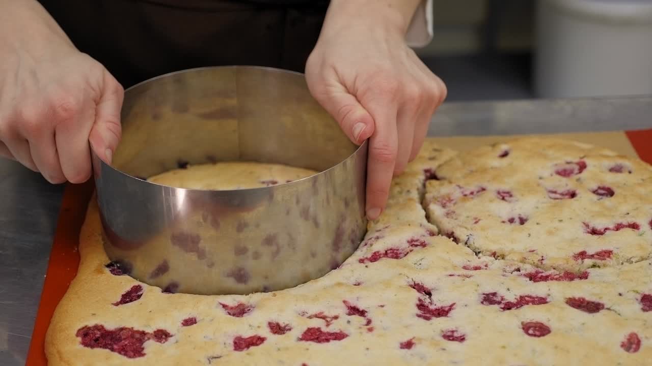 primer plano de un chef de pastelería cortando una forma redonda de una gran masa de galleta.