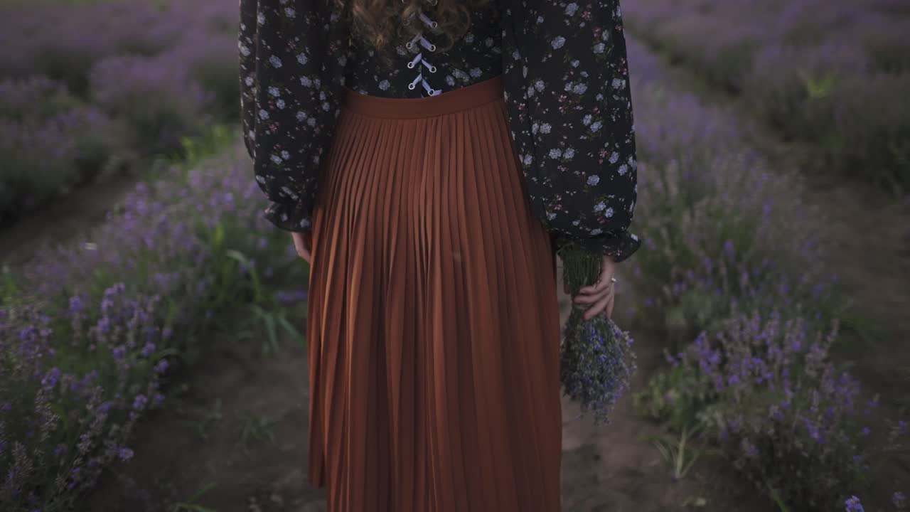 Rear view of a woman in dress holding basket with lavender flowers coming to her friend