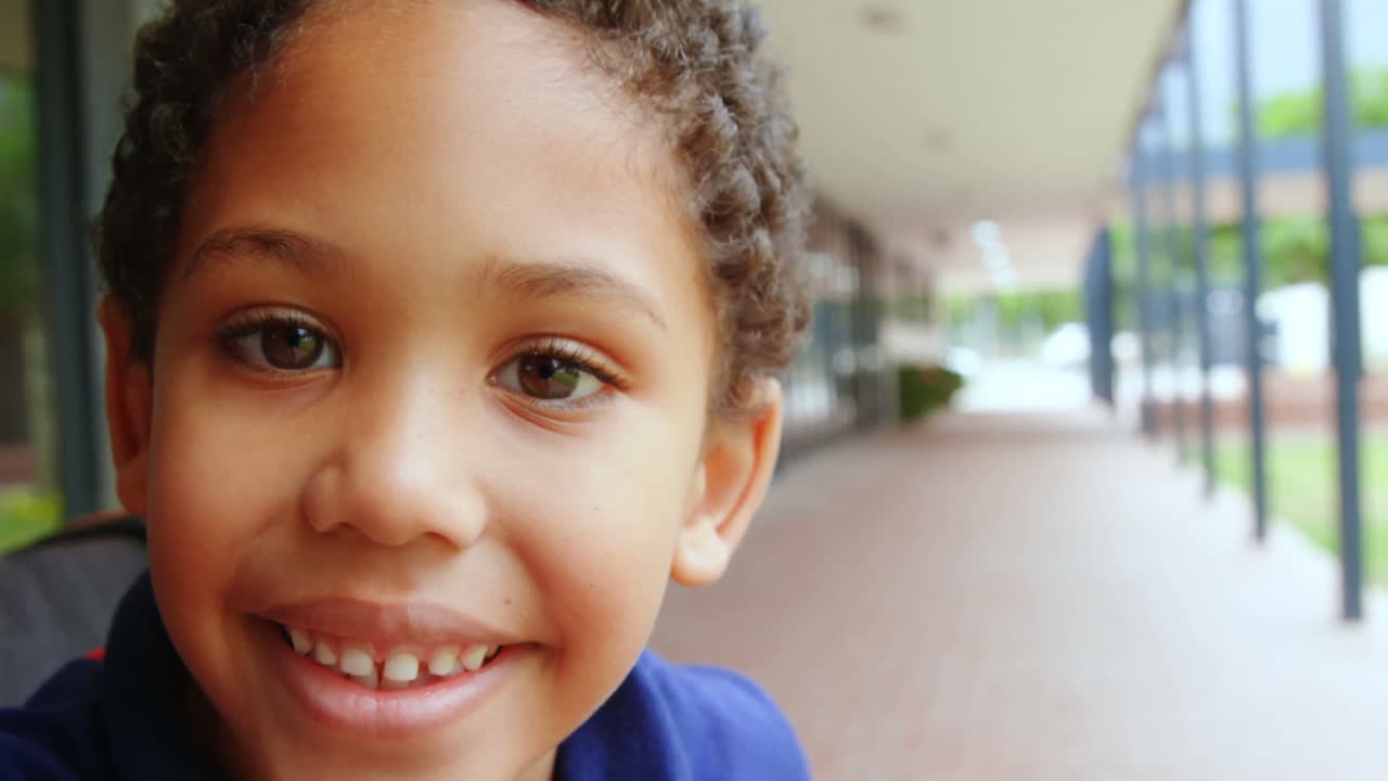 Close-up of happy disabled African American schoolboy sitting on wheelchair in school corridor 4k