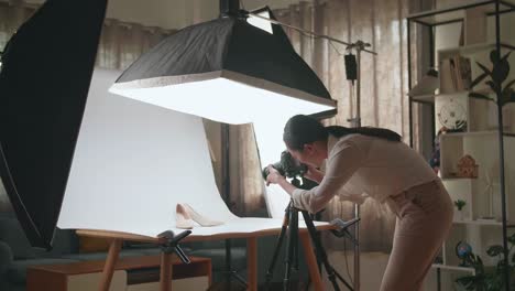 asian female photographer checking the photos of women's shoes after taking them in home studio