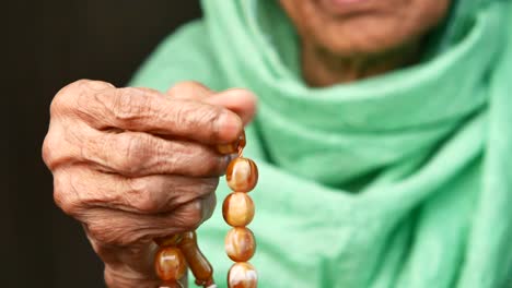 close up of an elderly woman's hand holding prayer beads