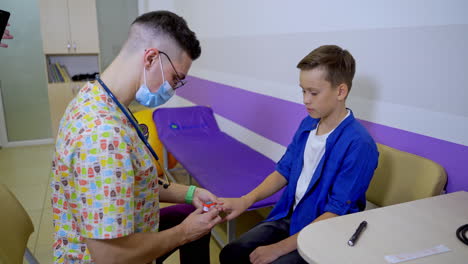 doctor listening to a teenage heart rate. special electrical appliance on finger. hi-tech technologies at pediatric clinic.