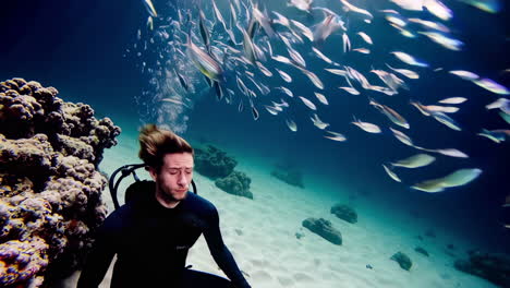 scuba diver surrounded by fish in coral reef
